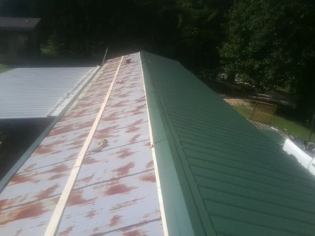 Old rusted panels beside newly installed green metal roofing — Wind Damage Roof Repair by Roofing Brothers in Dairy