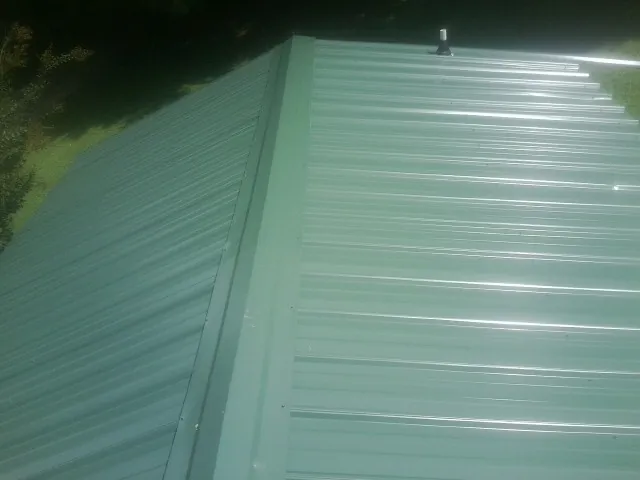New green metal panels meeting at the ridge of a roof — Flat Roof Repair work by our crew in Dairy