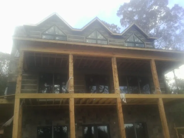 Dormers and porch framing on a large log home under construction — Roof Coating work by our crew in Dairy