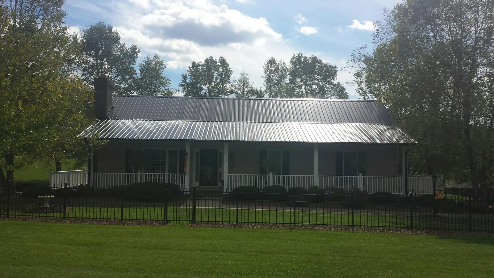 Gray metal roof on a brick ranch with a full width front porch in Dairy