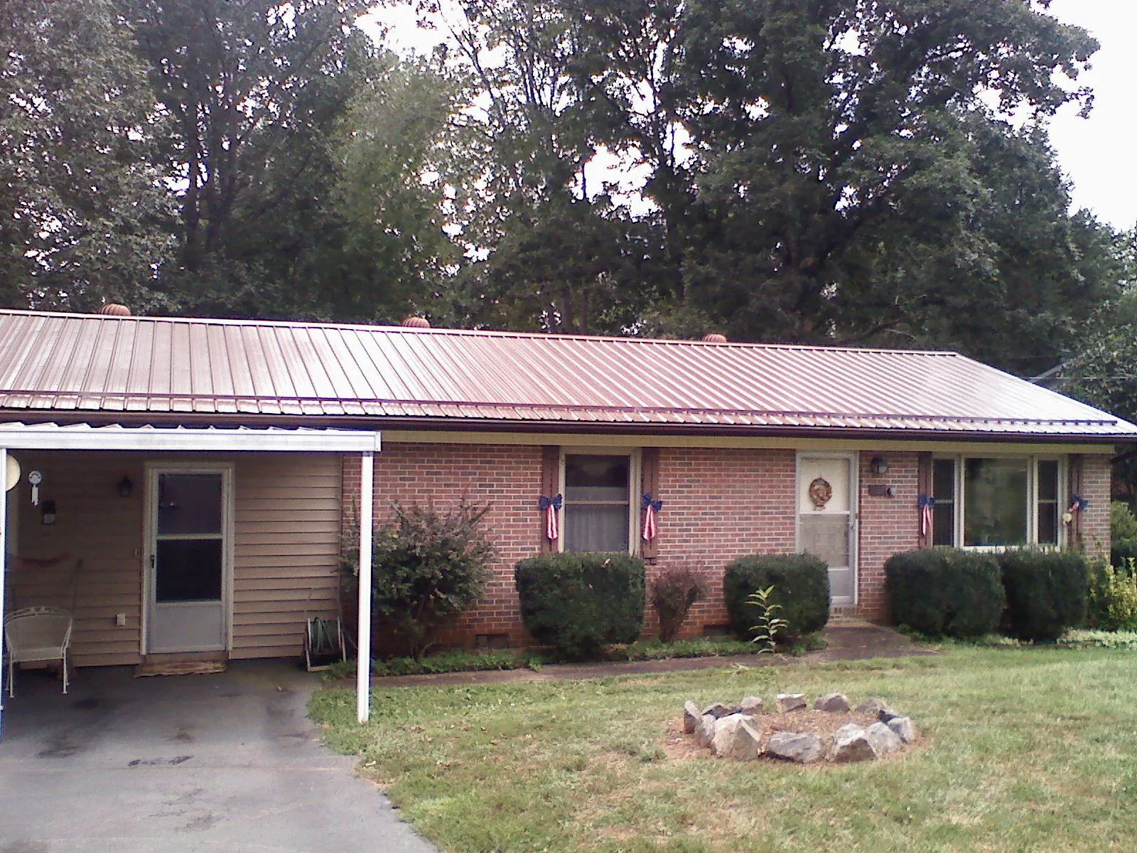 Bronze metal roof and carport on a brick ranch home — Roof Repair work by our crew in Dairy