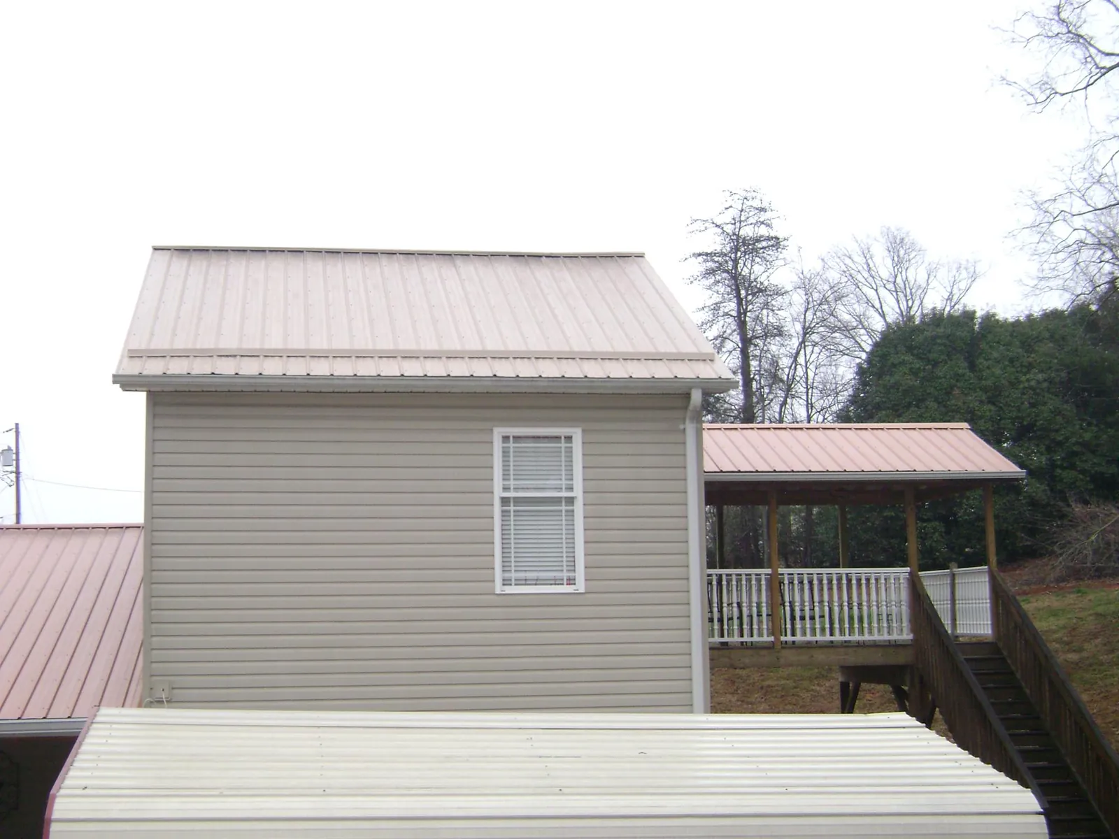 Tan metal roofs on a two story addition and attached porch, from a Roof Replacement job in Dairy